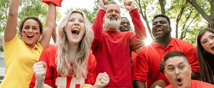 A group of hype fans cheer while tailgating